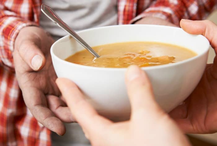 hands passing a bowl of soup